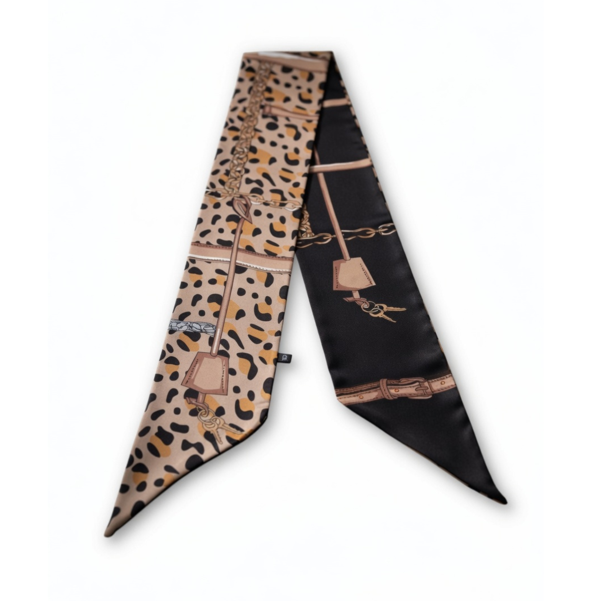 Ein schmales, langes Halstuch aus glänzendem Material, flach ausgelegt auf weißem Grund. Die eine Hälfte zeigt ein wildes Leopardenmuster in Beige und Braun, die andere Hälfte ist elegant Schwarz. Beide Seiten sind mit goldenen Ketten-, Gürtel- und Schlüsselmotiven verziert.