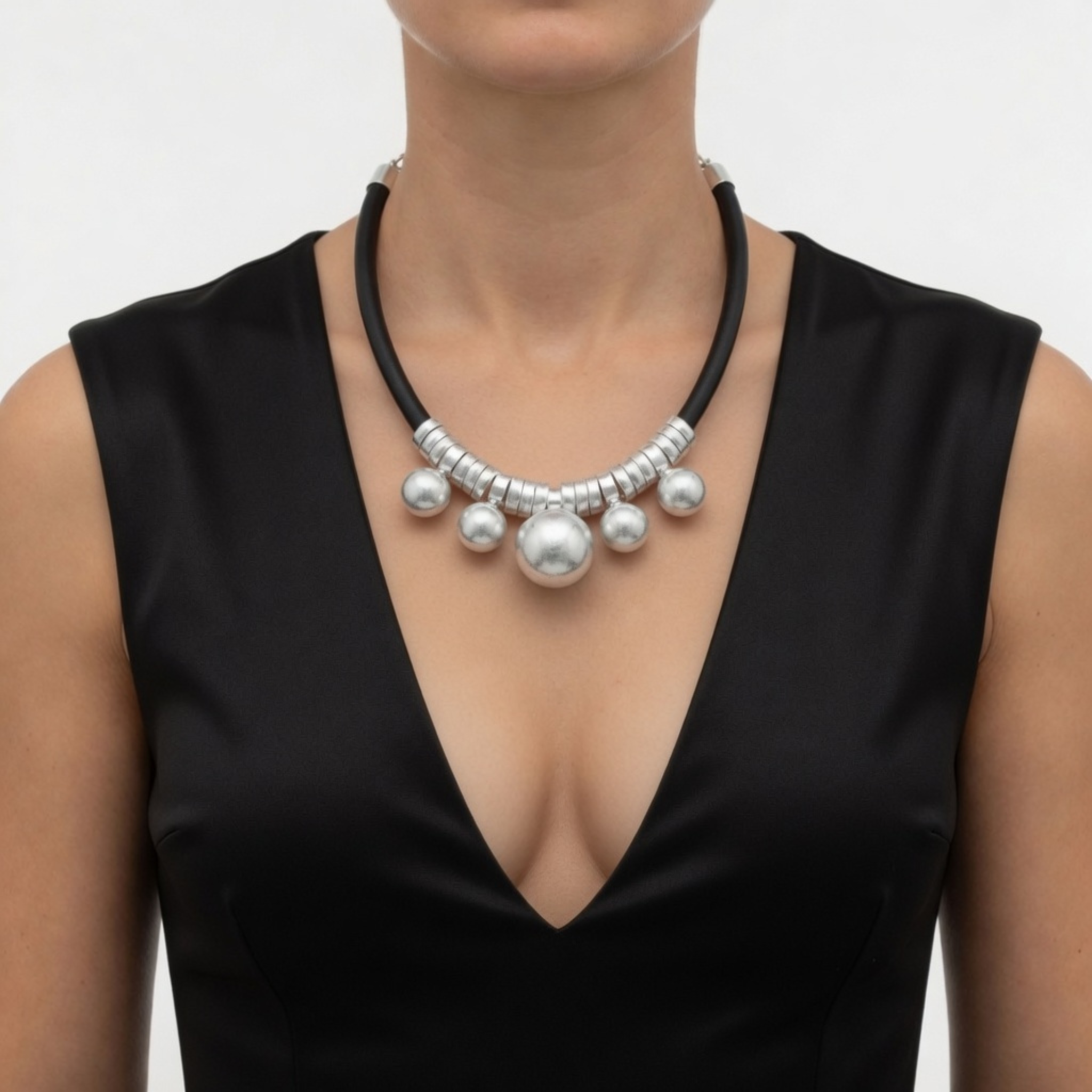 Nahaufnahme einer Kautschuk-Halskette mit silbernen Perlen und Metallelementen, präsentiert an einem Modell in einem eleganten, schwarzen Abendkleid mit tiefem V-Ausschnitt.