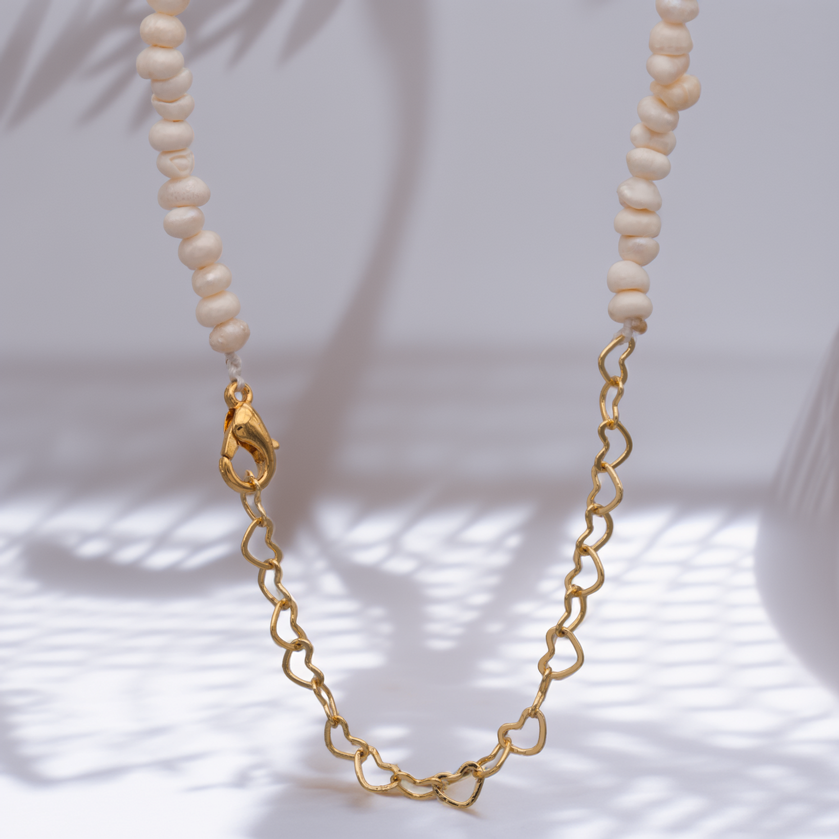 Süßwasser-Perlenkette in Weiß mit goldener Herzglieder-Kette – modernes, elegantes Schmuckstück.