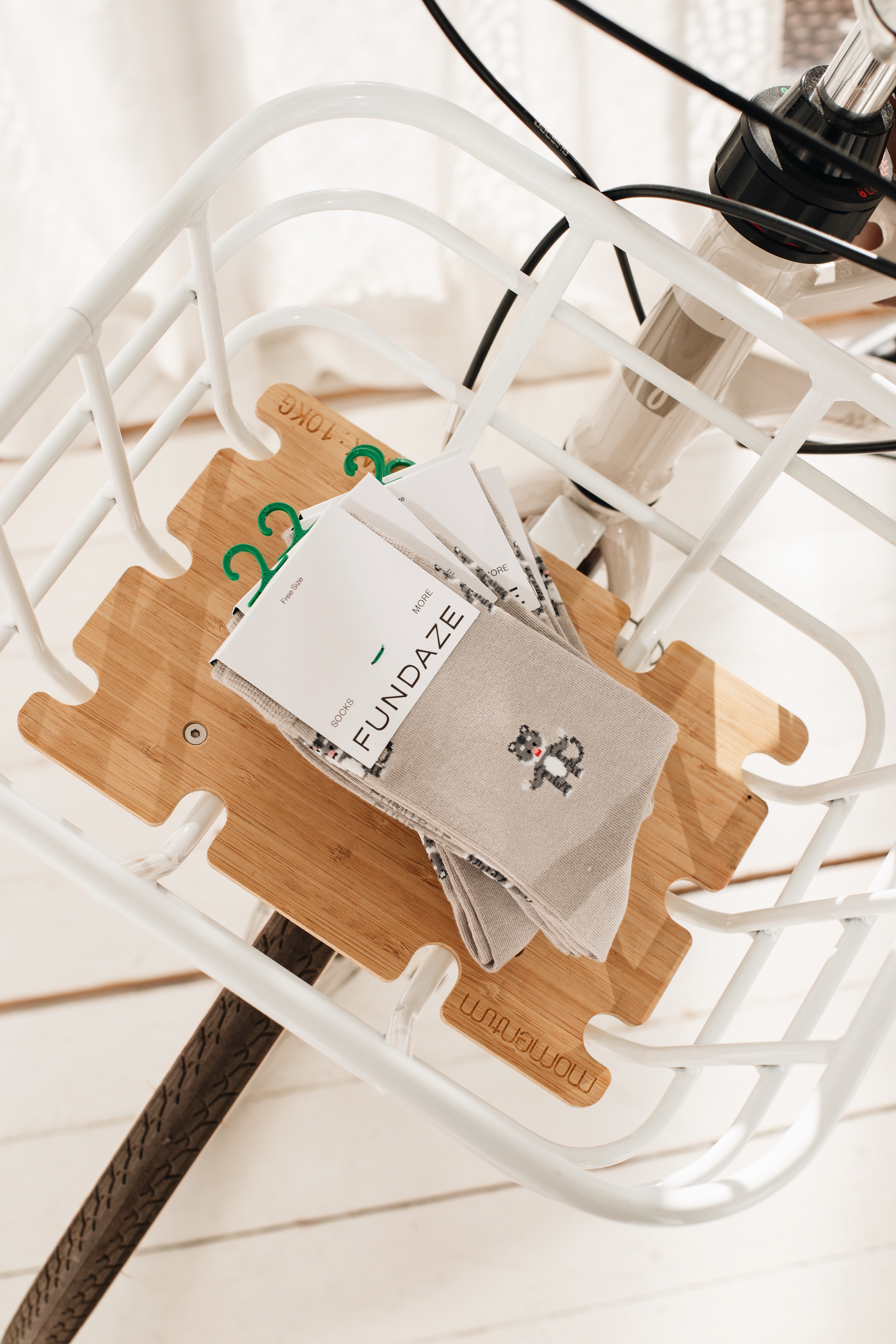 Mehrere Paar beige Socken mit einem flächendeckenden Muster aus kleinen, illustrierten Löwen-Köpfen in Braun und Orange, originalverpackt mit Etikett.