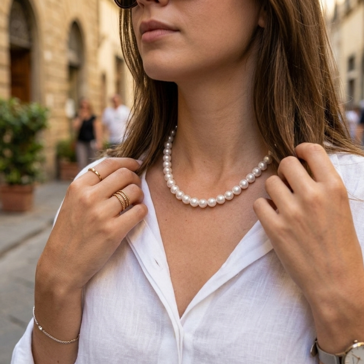 Kurze weiße Perlenkette, getragen zu weißer Bluse in eleganter Streetstyle-Ansicht
