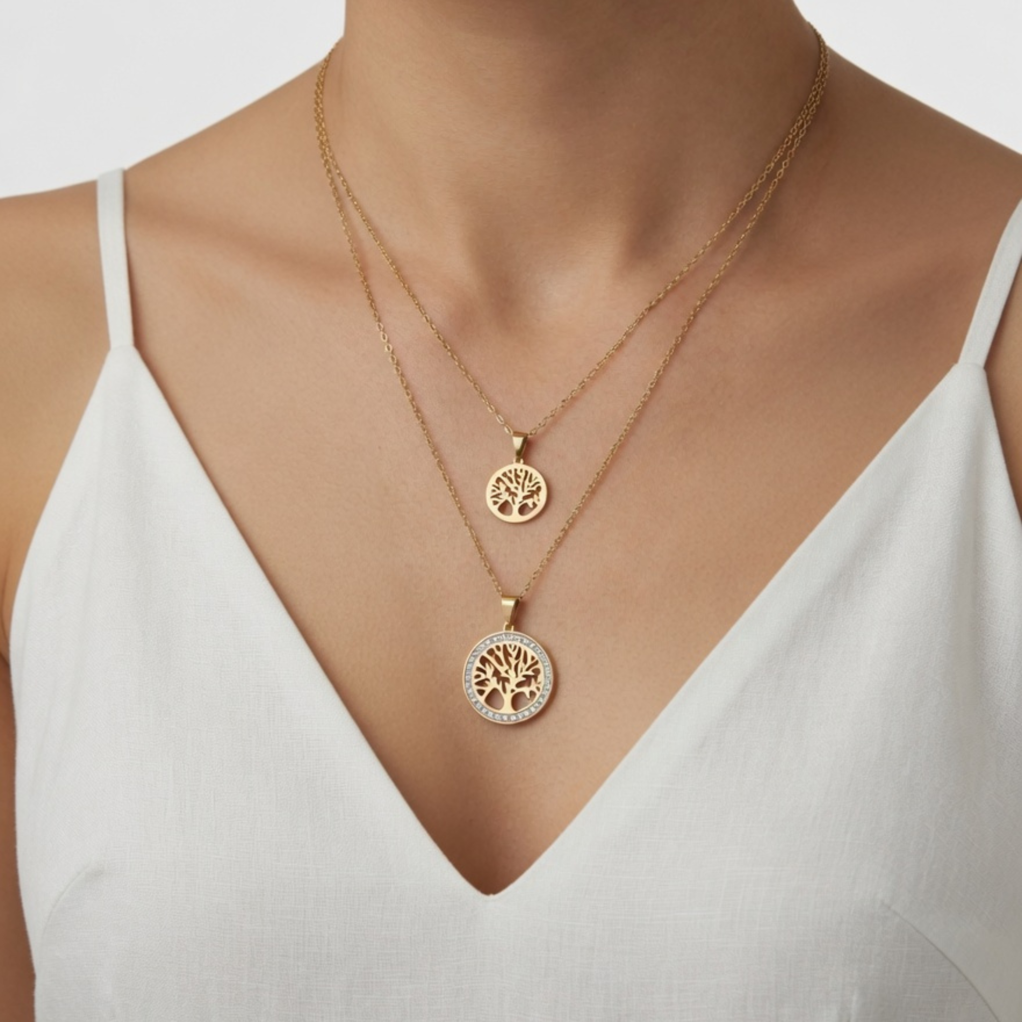 Modell mit V-Ausschnitt präsentiert ein Set aus zwei goldfarbenen Ketten mit Baum des Lebens Motiven, kombiniert in unterschiedlichen Längen.