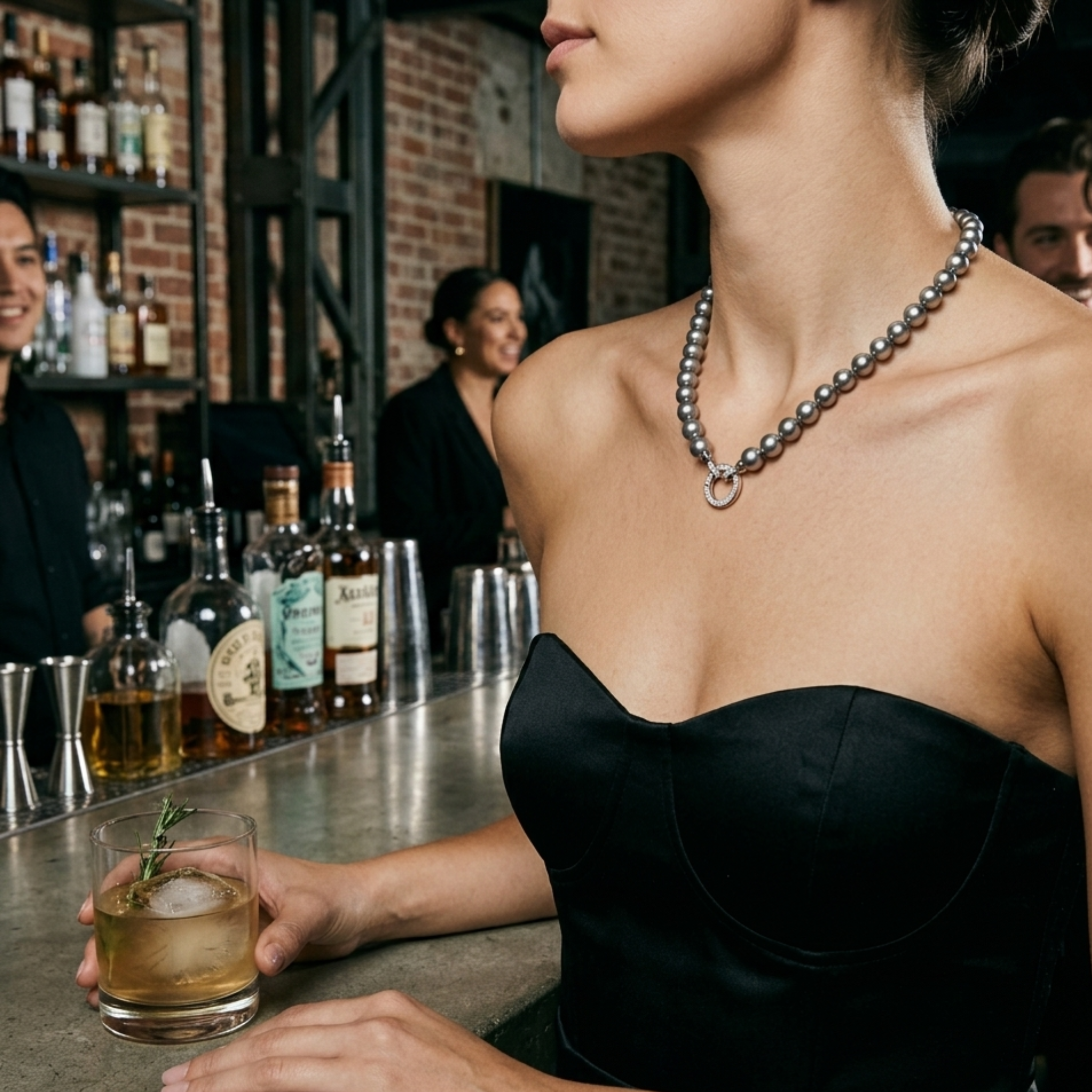 Graue Perlenkette mit silberfarbenem Ringdetail, elegant getragen in Bar-Atmosphäre
