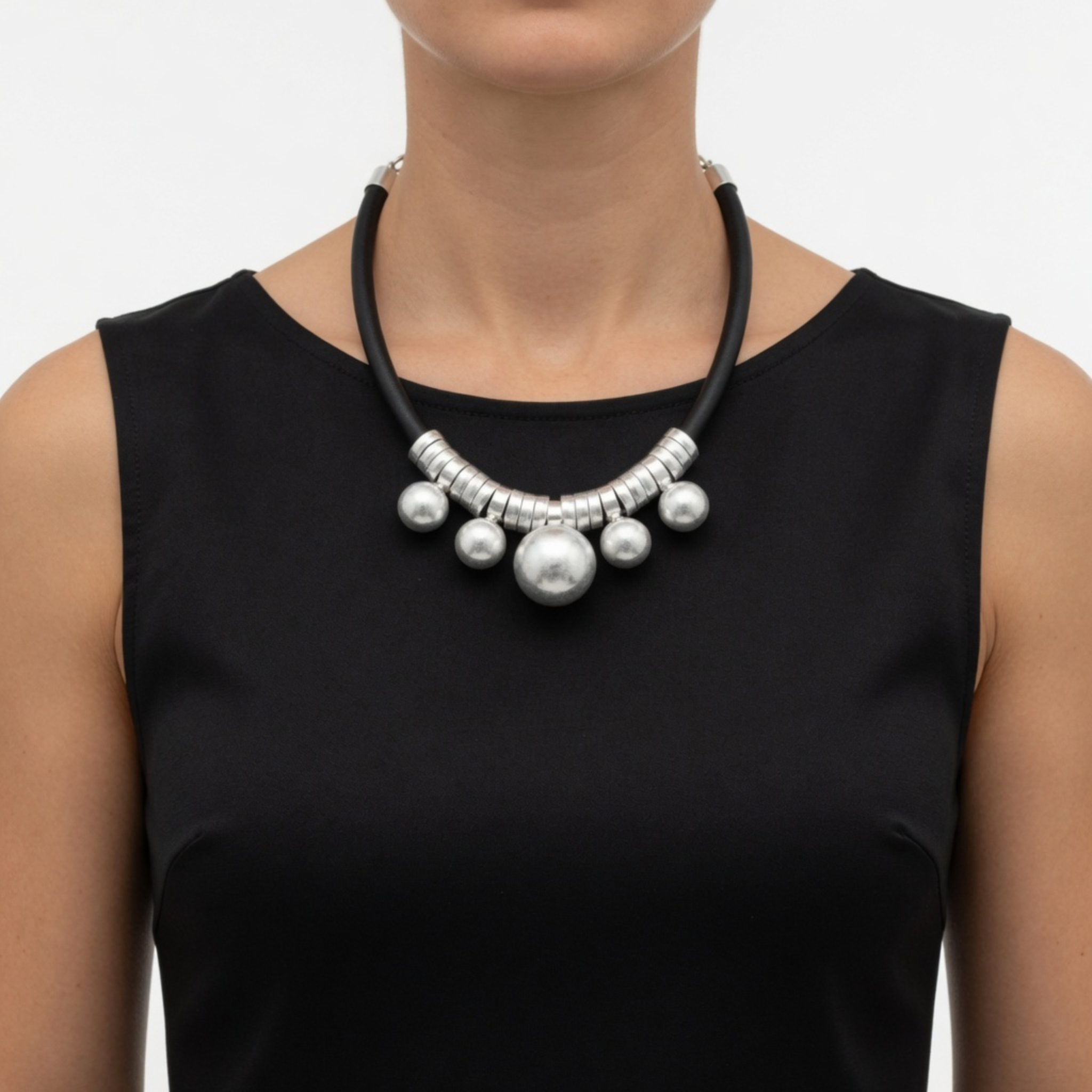 Frontale Ansicht einer Kautschuk-Kette mit silbernen Elementen, getragen von einem Modell mit einem klassischen, hochgeschlossenen schwarzen Rundhals-Oberteil.