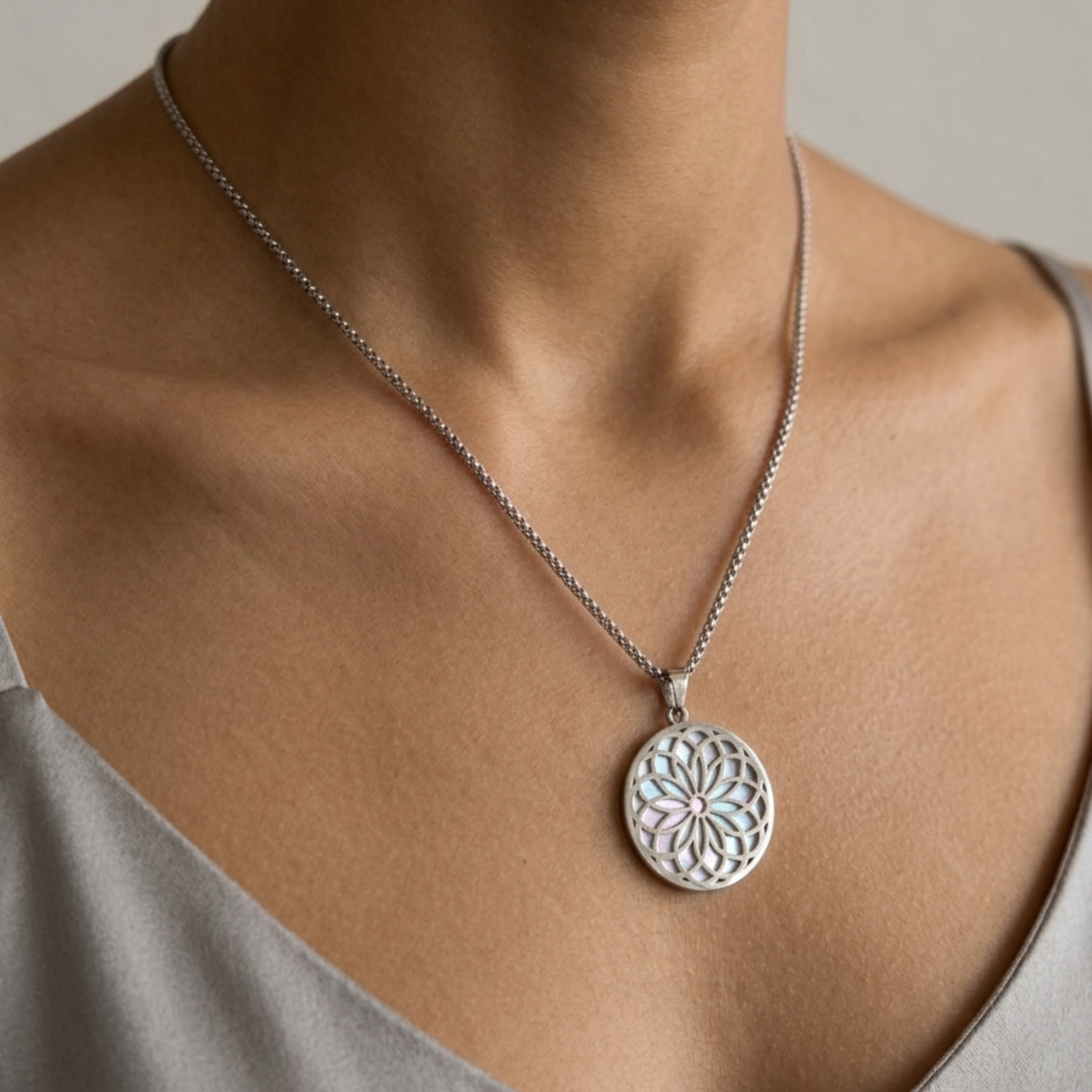 Silberfarbene Kette mit rundem Blumen-Mandala-Anhänger auf heller Kleidung