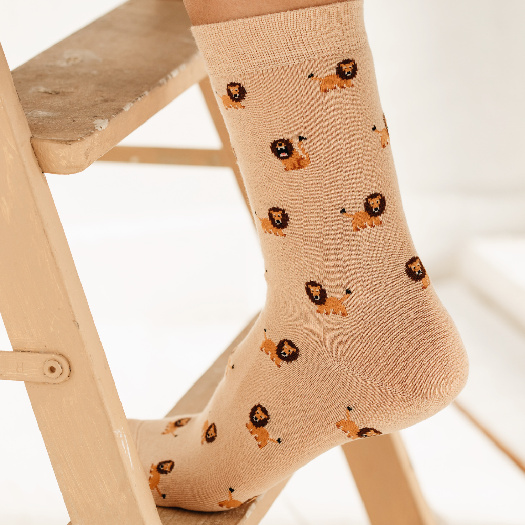 Trendige beige Socken mit Allover-Löwen-Print. Die hochwertige Verpackung mit dem Logo 'FUNDAZE' unterstreicht das moderne Design der Motiv-Socken.