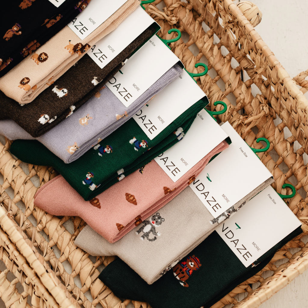 Fliederfarbene Motivsocken mit kleinen Corgis beim Radfahren – Detailansicht von Socke und Sneaker
