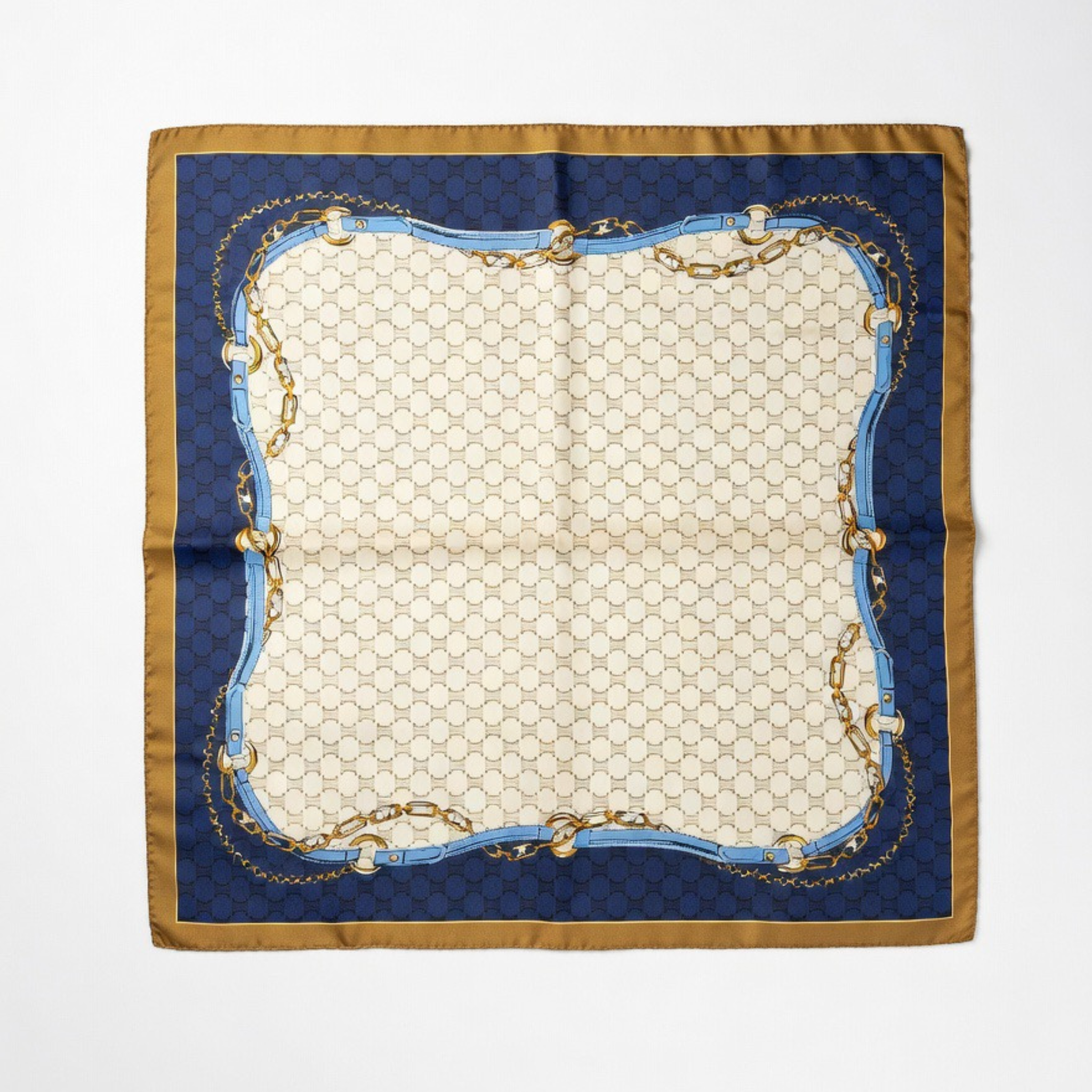 Das quadratische Halstuch flach ausgebreitet auf weißem Grund. Es präsentiert ein symmetrisches Design mit cremefarbenem Zentrum, einem breiten marineblauen Rahmen und umlaufenden Motiven von goldfarbenen Ketten und hellblauen Gürtel-Elementen mit braunem Saum.